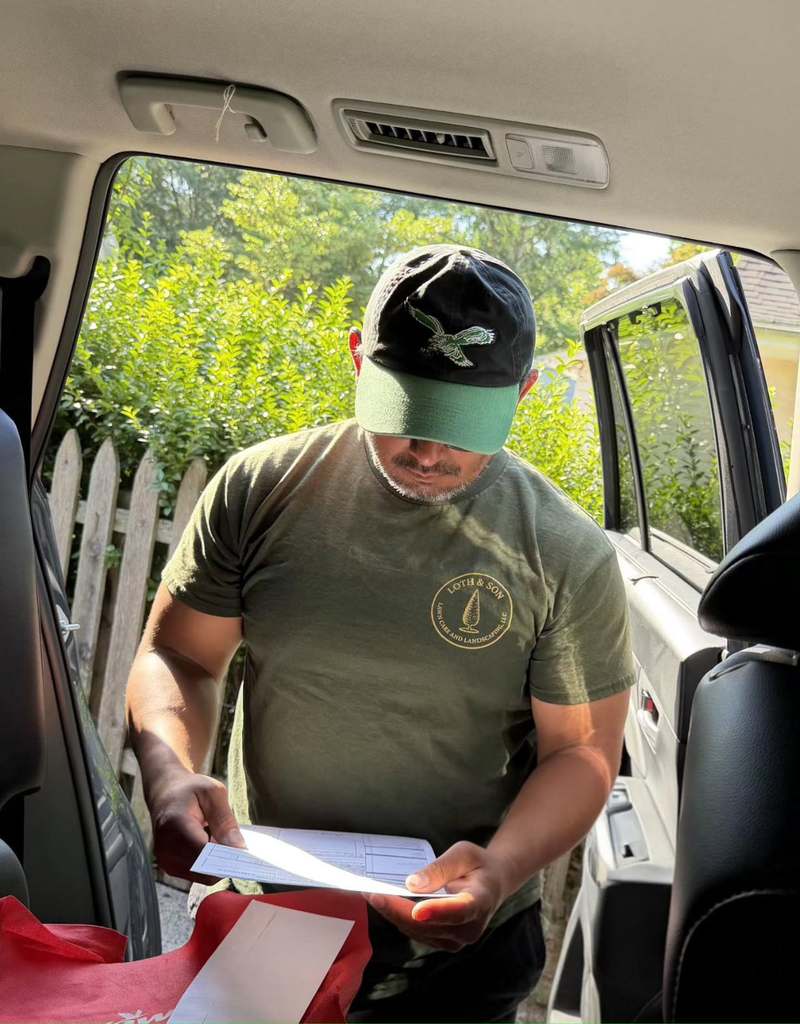 Rathana Yen standing at his truck in a Loth & Son shirt, reading through a written work order.